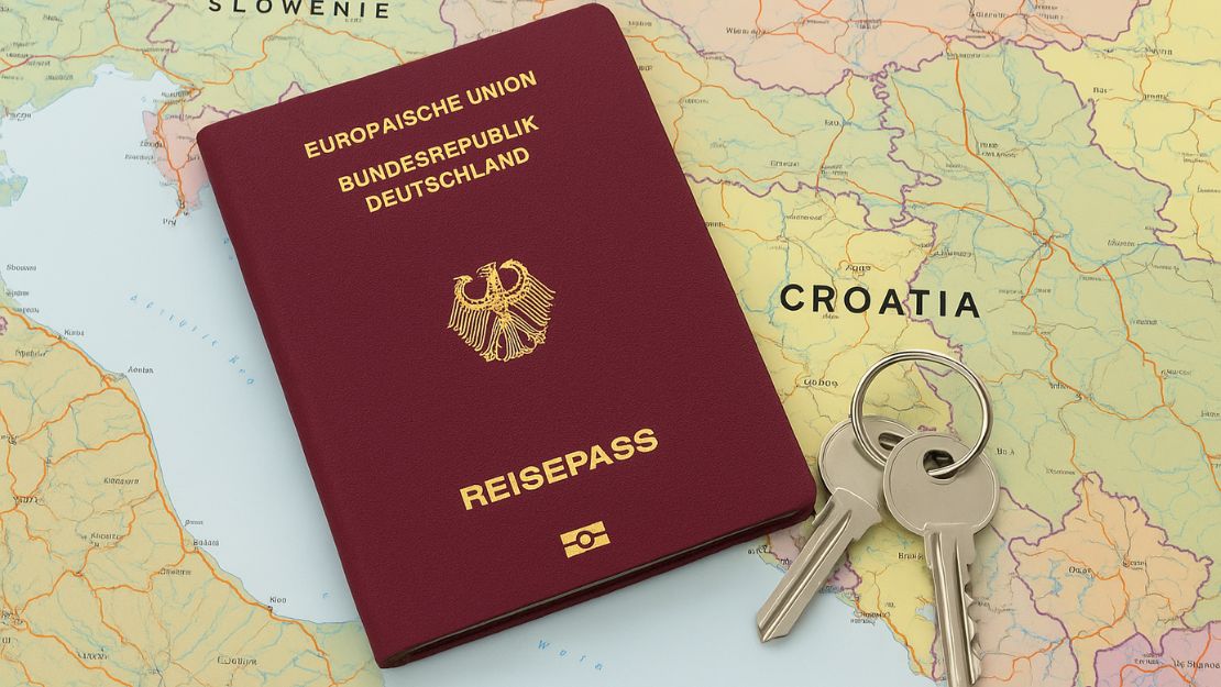 Passaporto tedesco e chiavi di casa su uno sfondo con la mappa della Croazia